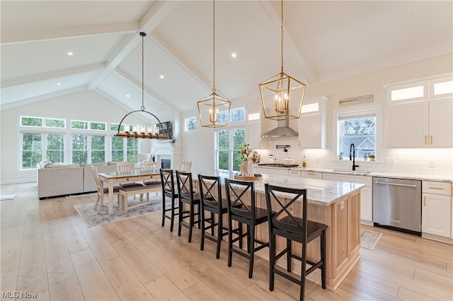 kitchen with appliances with stainless steel finishes, light stone counters, white cabinets, a kitchen island, and pendant lighting