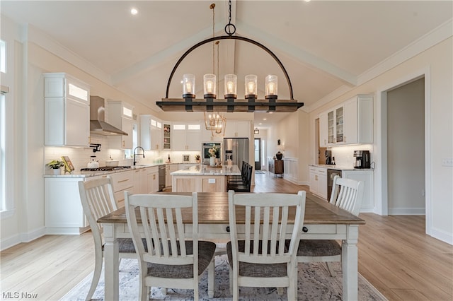 dining area with sink, a chandelier, high vaulted ceiling, and light hardwood / wood-style floors