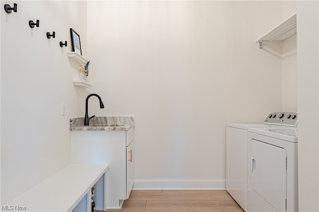 washroom with washing machine and clothes dryer and light wood-type flooring