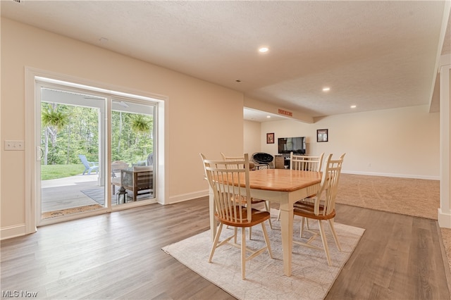 dining space with a textured ceiling and light hardwood / wood-style floors