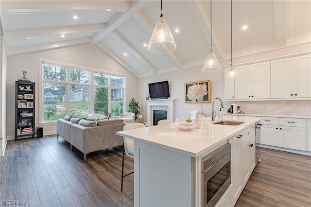 kitchen with dark hardwood / wood-style flooring, stainless steel microwave, sink, and a kitchen island with sink