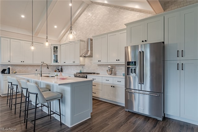 kitchen with dark wood-type flooring, wall chimney range hood, beamed ceiling, and stainless steel appliances