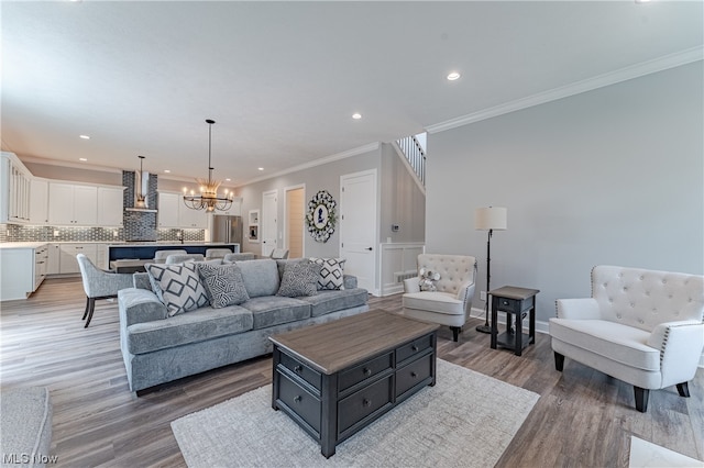 living room with crown molding, an inviting chandelier, and hardwood / wood-style flooring