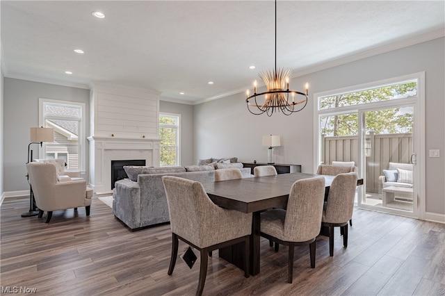 dining space featuring a wealth of natural light, a large fireplace, dark wood-type flooring, and an inviting chandelier