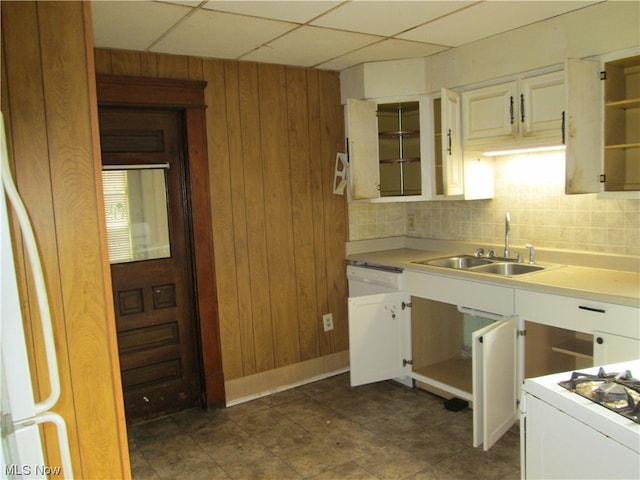 kitchen featuring tasteful backsplash, wooden walls, a paneled ceiling, sink, and dark tile floors