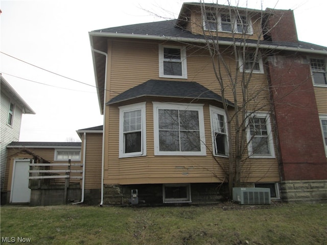 back of house with central air condition unit and a yard