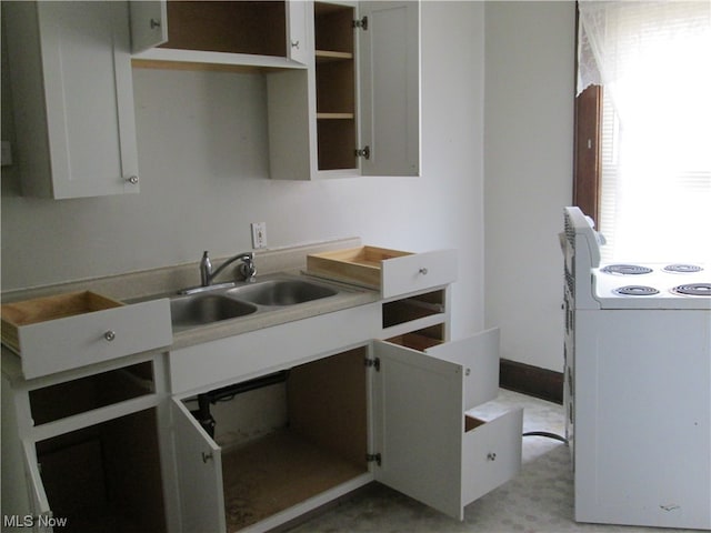 kitchen with stove, white cabinetry, and sink