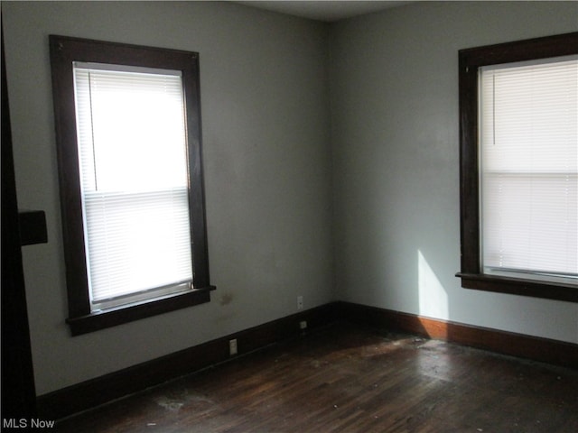 unfurnished room featuring dark wood-type flooring and a wealth of natural light