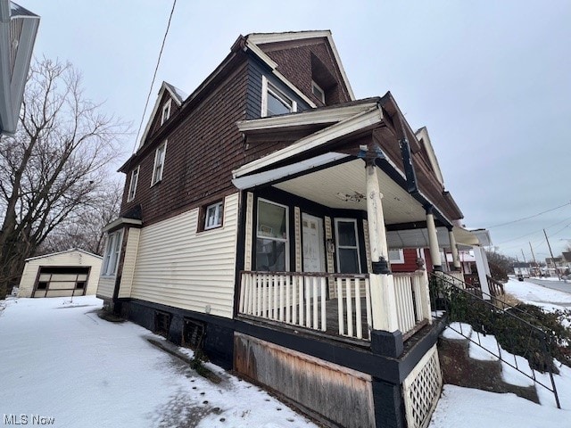 view of snow covered exterior featuring covered porch and a garage