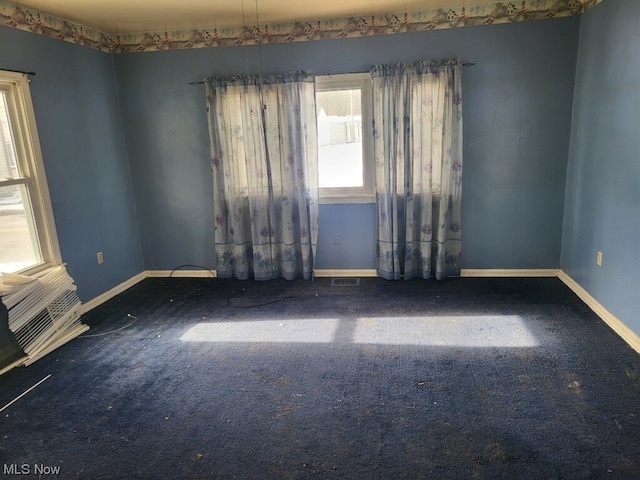 spare room featuring dark carpet and a wealth of natural light