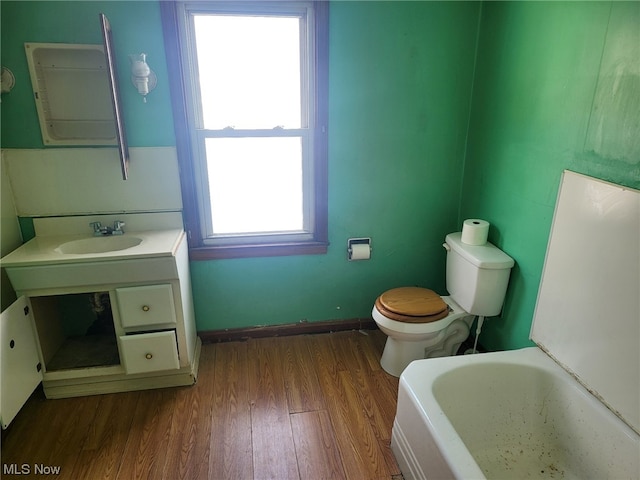 bathroom featuring toilet, hardwood / wood-style floors, vanity, and a tub