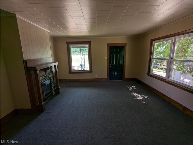 unfurnished living room with ornamental molding, dark colored carpet, and a fireplace