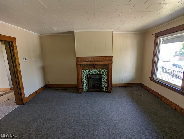 unfurnished living room featuring ornamental molding, dark colored carpet, and a fireplace