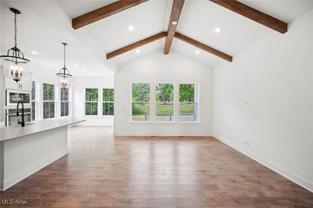 unfurnished living room with a notable chandelier, a sink, wood finished floors, beamed ceiling, and baseboards