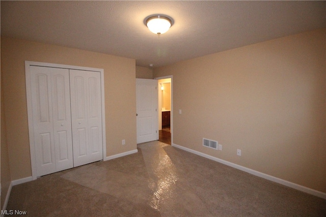 unfurnished bedroom featuring dark colored carpet and a closet