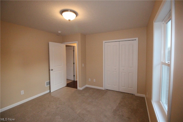 unfurnished bedroom featuring a closet and light carpet