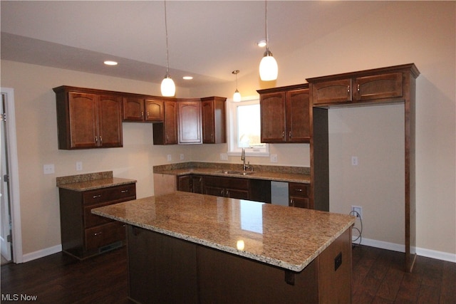 kitchen featuring light stone counters, a kitchen island, dark hardwood / wood-style floors, pendant lighting, and sink