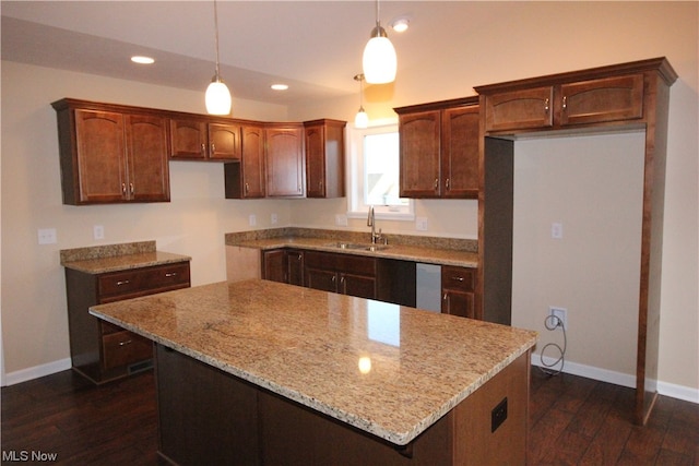 kitchen with a center island, decorative light fixtures, dark hardwood / wood-style flooring, sink, and light stone countertops