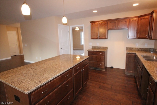 kitchen with ceiling fan, pendant lighting, dark wood-type flooring, and light stone counters