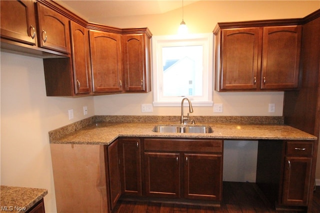 kitchen with pendant lighting, sink, dark wood-type flooring, and light stone counters