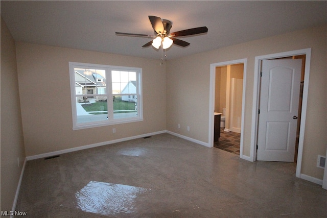 unfurnished bedroom with ceiling fan, dark colored carpet, and ensuite bathroom