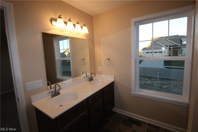 bathroom with double sink, a wealth of natural light, large vanity, and tile floors