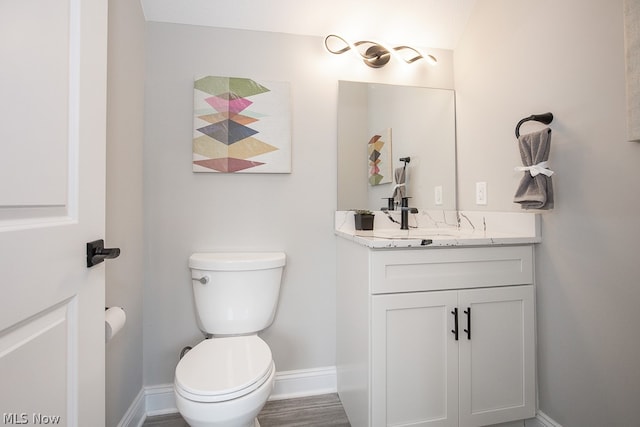 bathroom featuring hardwood / wood-style floors, toilet, and vanity with extensive cabinet space