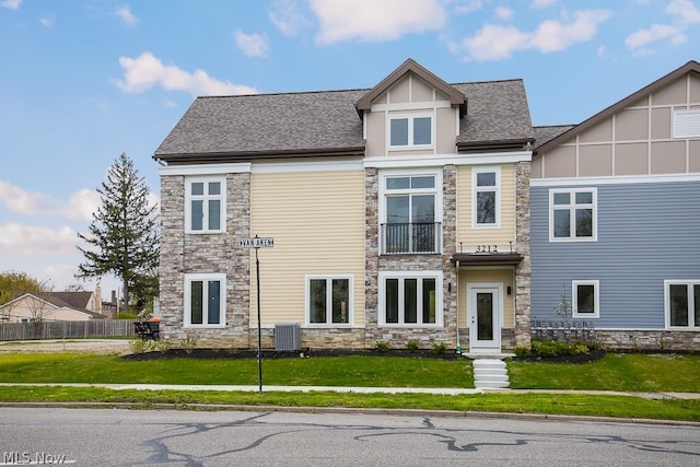 view of front of property featuring a balcony, central air condition unit, and a front lawn