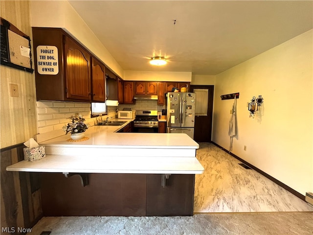 kitchen featuring kitchen peninsula, a breakfast bar, stainless steel appliances, and sink