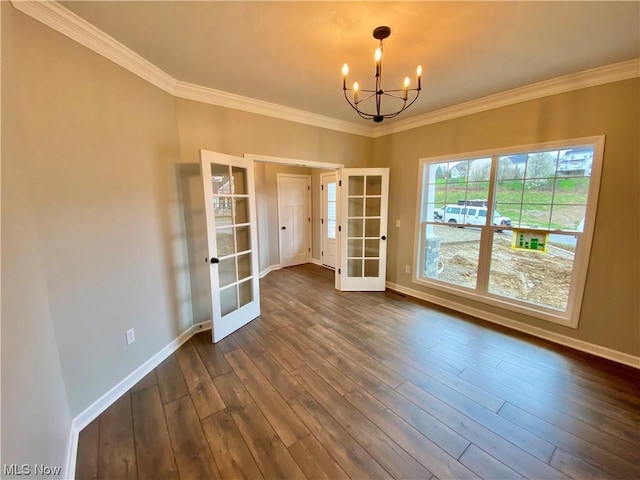 empty room with baseboards, french doors, ornamental molding, dark wood-style floors, and an inviting chandelier