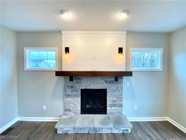 room details with visible vents, baseboards, wood finished floors, and a glass covered fireplace