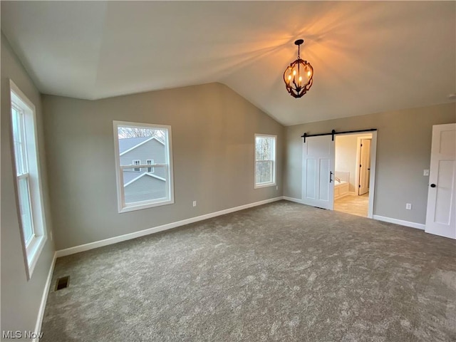 unfurnished bedroom featuring lofted ceiling, visible vents, a barn door, light carpet, and a chandelier