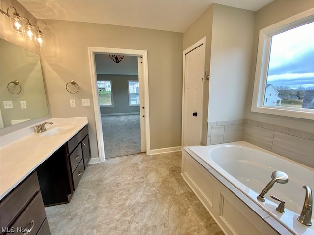 full bathroom with baseboards, a bath, and vanity