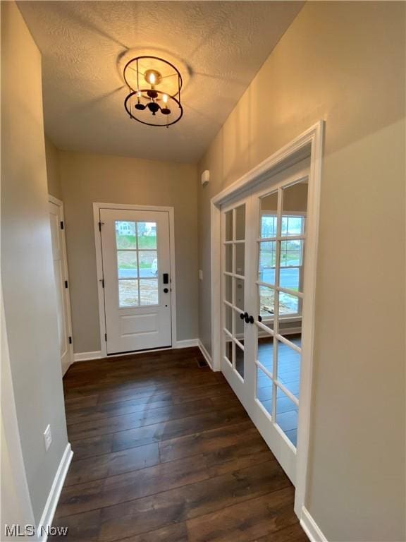 doorway with dark wood-style flooring, french doors, a textured ceiling, and baseboards