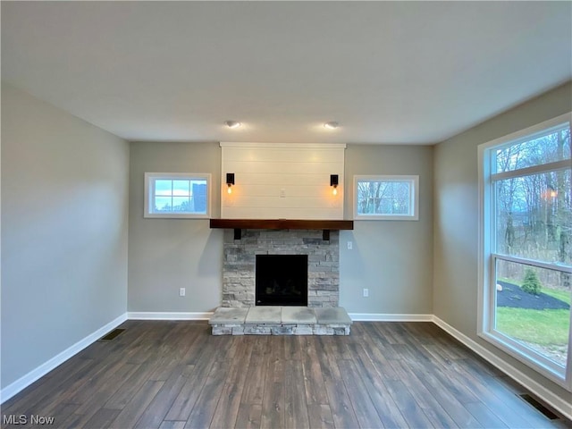 unfurnished living room with a fireplace, dark wood finished floors, visible vents, and baseboards