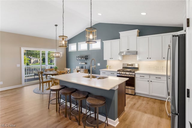 kitchen with lofted ceiling, white cabinets, sink, appliances with stainless steel finishes, and light hardwood / wood-style floors