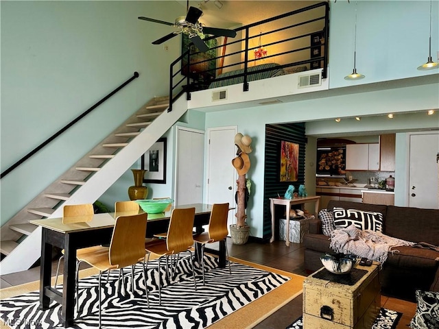 tiled living room with stairs, ceiling fan, a towering ceiling, and visible vents