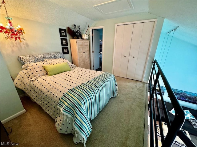 carpeted bedroom featuring attic access, baseboards, lofted ceiling, a textured ceiling, and a closet