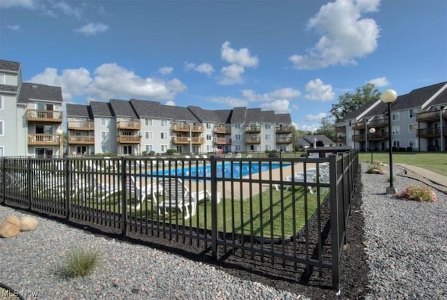 view of gate with a residential view, fence, and a community pool