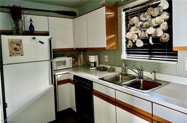 kitchen featuring white appliances, a sink, white cabinets, light countertops, and decorative backsplash