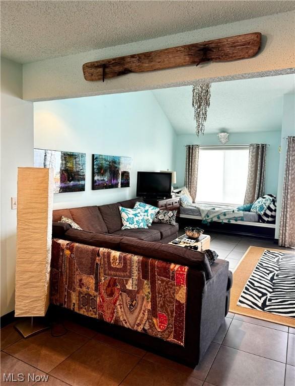 living area featuring vaulted ceiling, dark tile patterned floors, and a textured ceiling