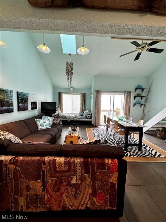 living room with ceiling fan, vaulted ceiling with skylight, and a healthy amount of sunlight