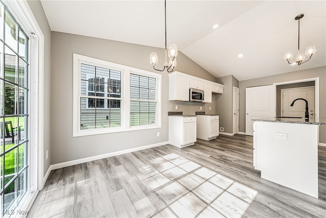 kitchen featuring an inviting chandelier, white cabinetry, pendant lighting, and vaulted ceiling