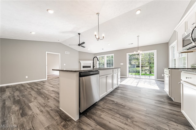 kitchen with white cabinets, stainless steel appliances, a center island with sink, and vaulted ceiling