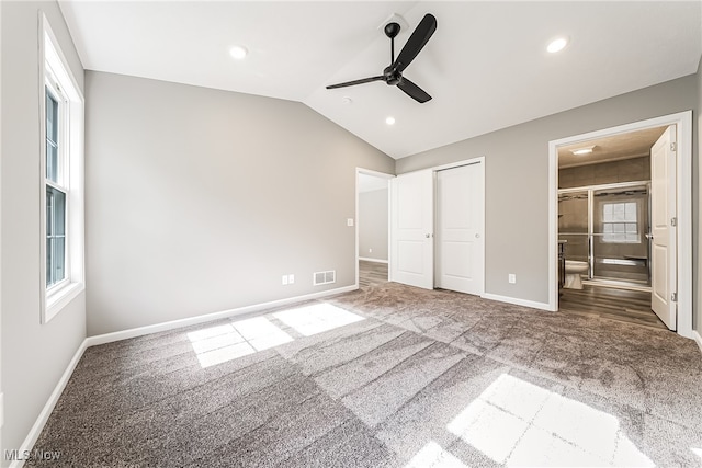 unfurnished bedroom featuring lofted ceiling, ensuite bathroom, carpet, and ceiling fan