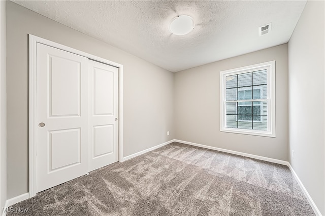 unfurnished bedroom with a textured ceiling, carpet flooring, and a closet