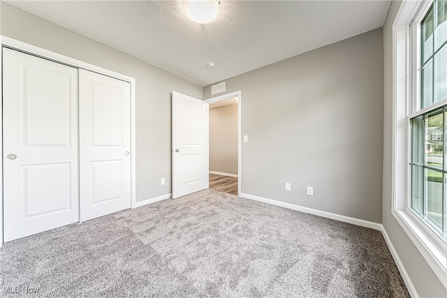 unfurnished bedroom featuring a closet, carpet, and a textured ceiling