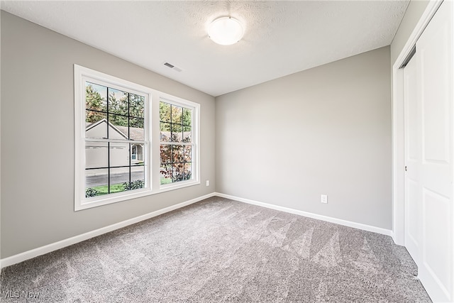 carpeted spare room featuring a textured ceiling