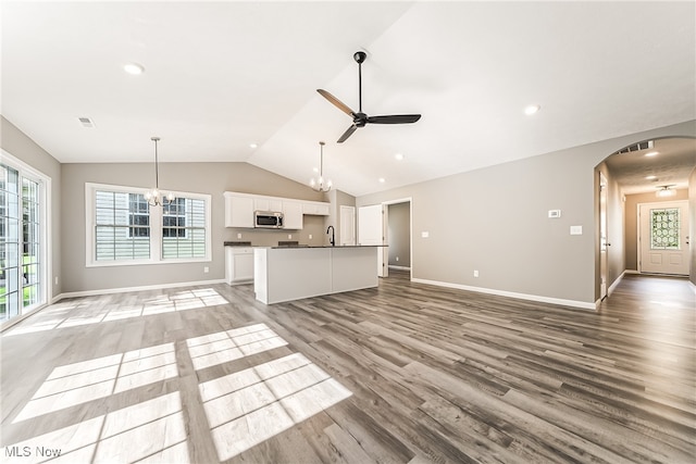 unfurnished living room with hardwood / wood-style floors, sink, ceiling fan with notable chandelier, and vaulted ceiling