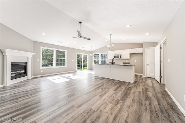 unfurnished living room featuring sink, vaulted ceiling, light wood-type flooring, and ceiling fan